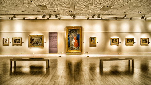 Wide view of an art gallery with paintings displayed along the walls