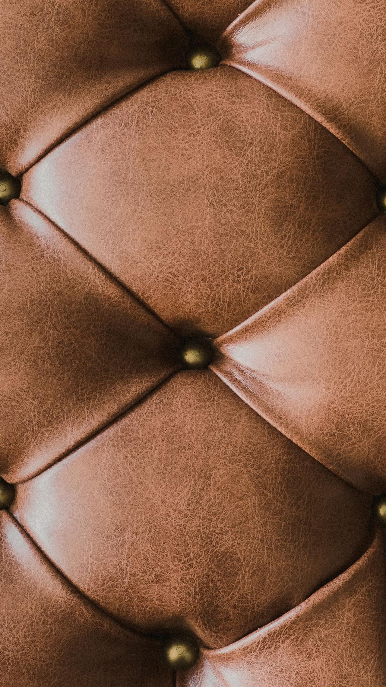 Close-up view of tufted brown leather upholstery with buttons and folds.