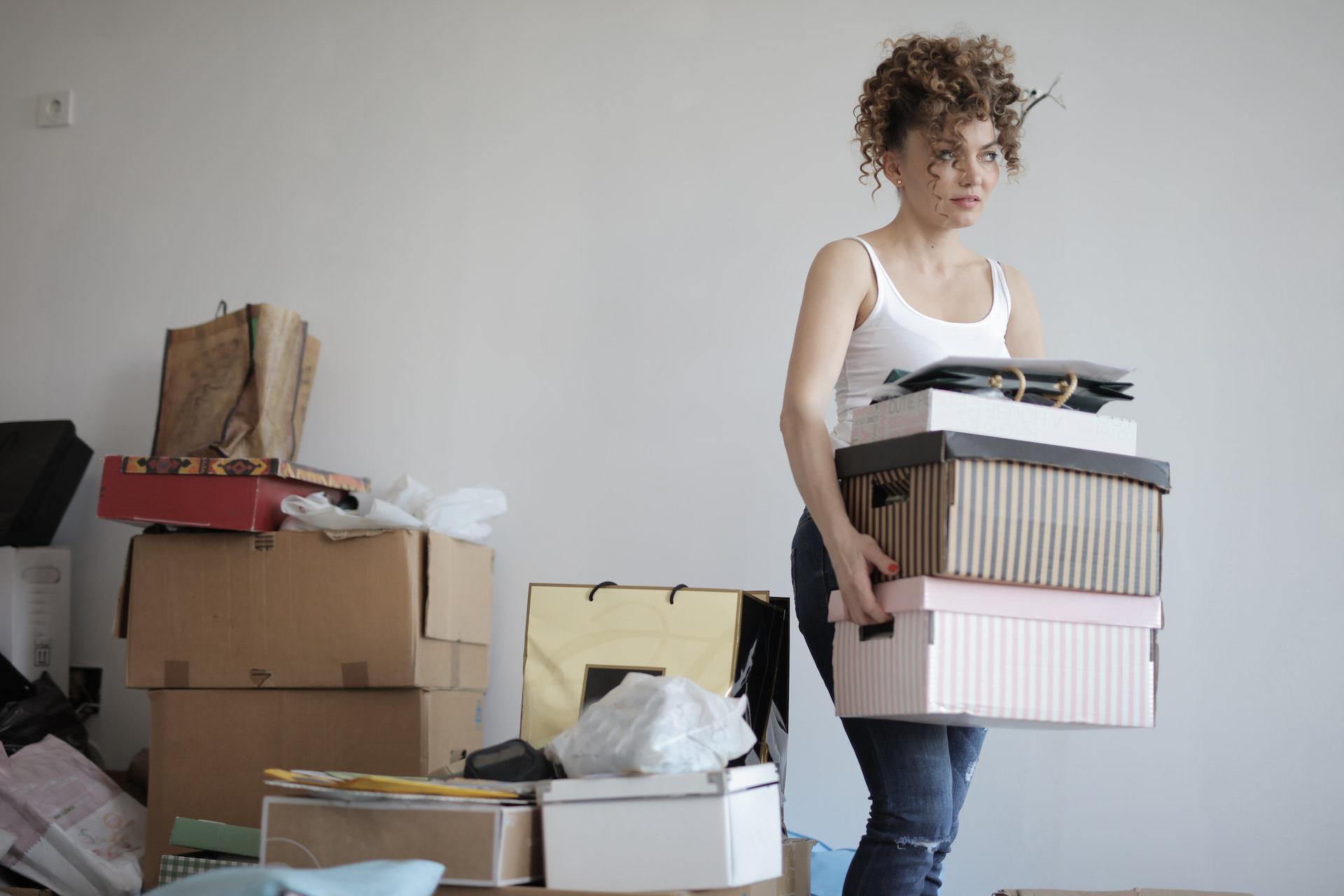 a perturbed looking woman carries boxes of belongings during a move