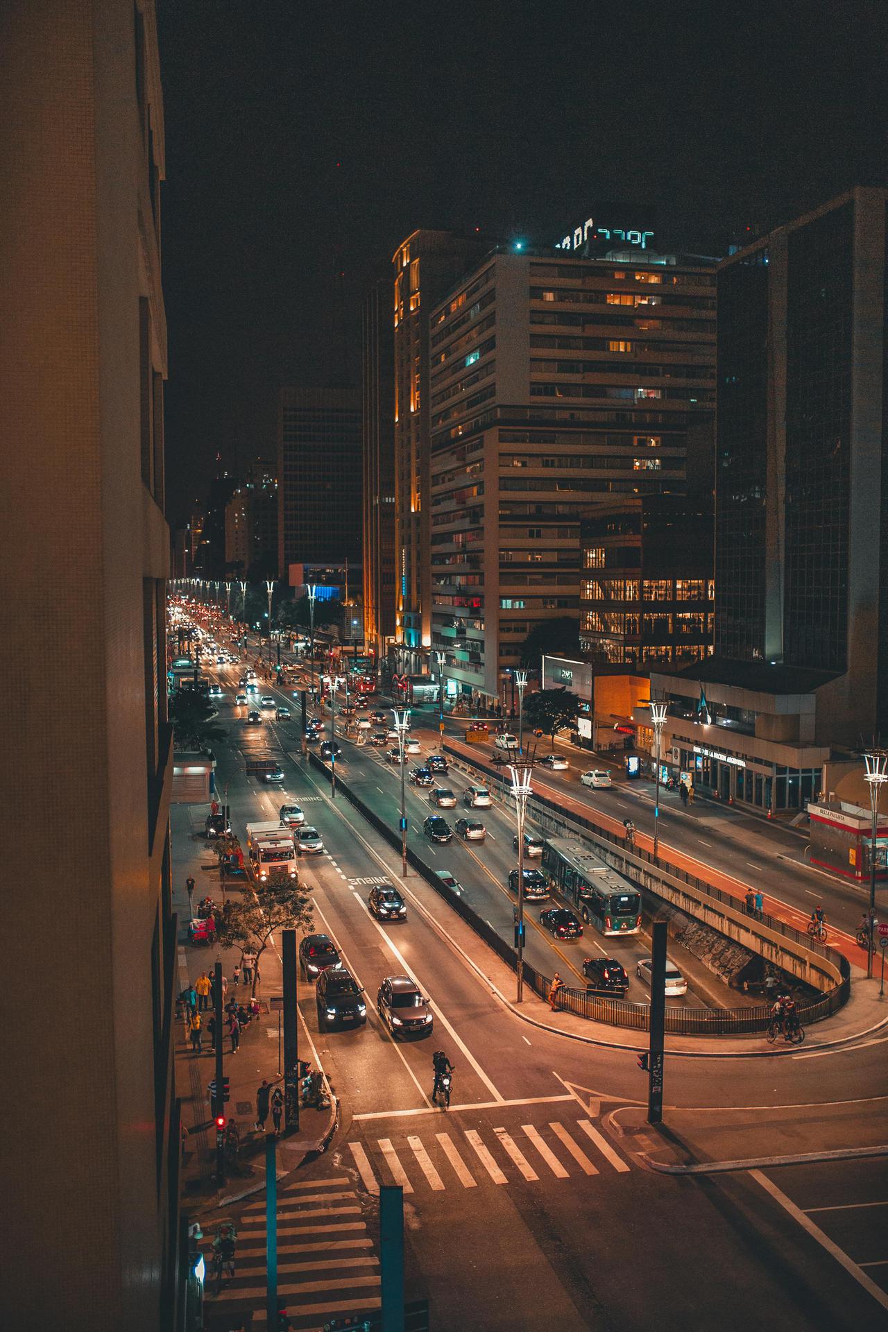 A vibrant night scene capturing the bustling traffic on Paulista Avenue in São Paulo, Brazil.