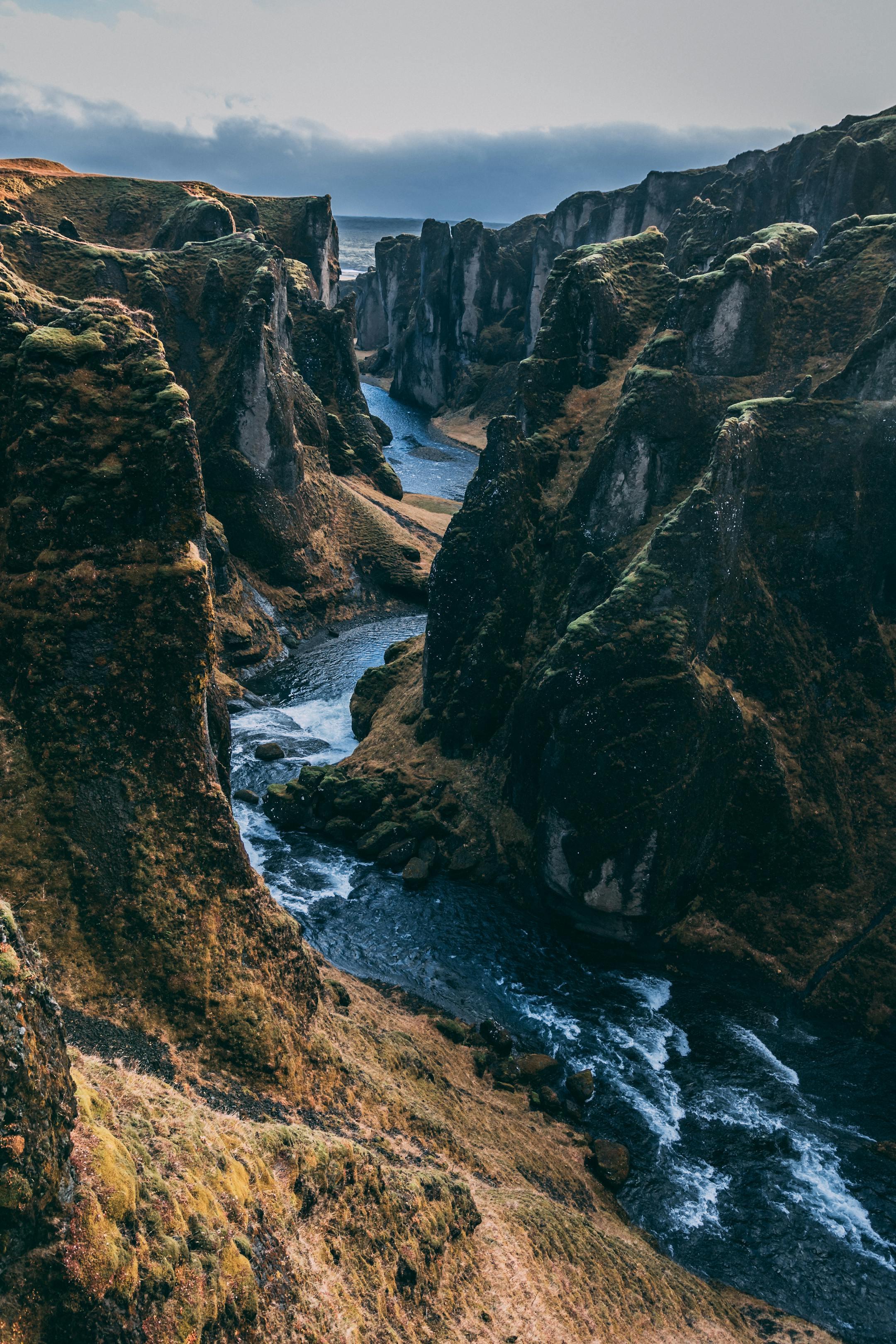 Breathtaking view of the Fjadrargljufur Canyon with a flowing river and steep rocky cliffs.