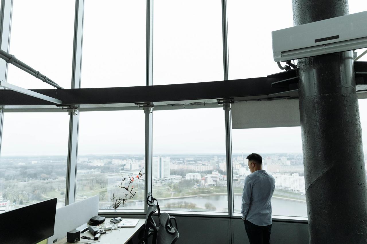 Businessman stands in a high-rise office with a panoramic city view, embodying modern corporate environment.