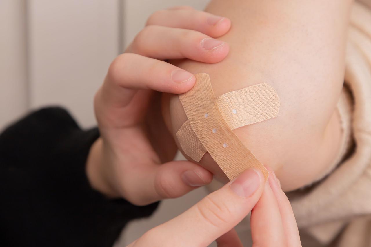 A person bandages another person's elbow.