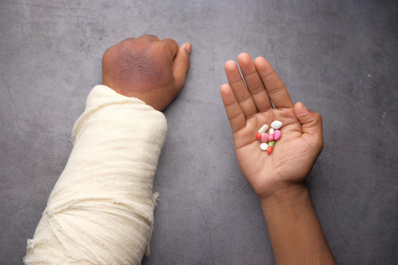 injured painful hand with bandage and medical pills on hand 