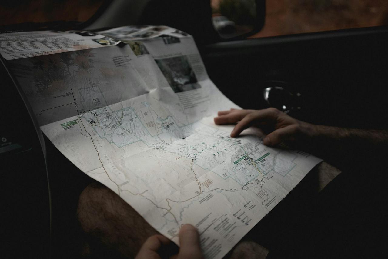 A person using a map for navigation inside a vehicle, hinting at exploration and travel.