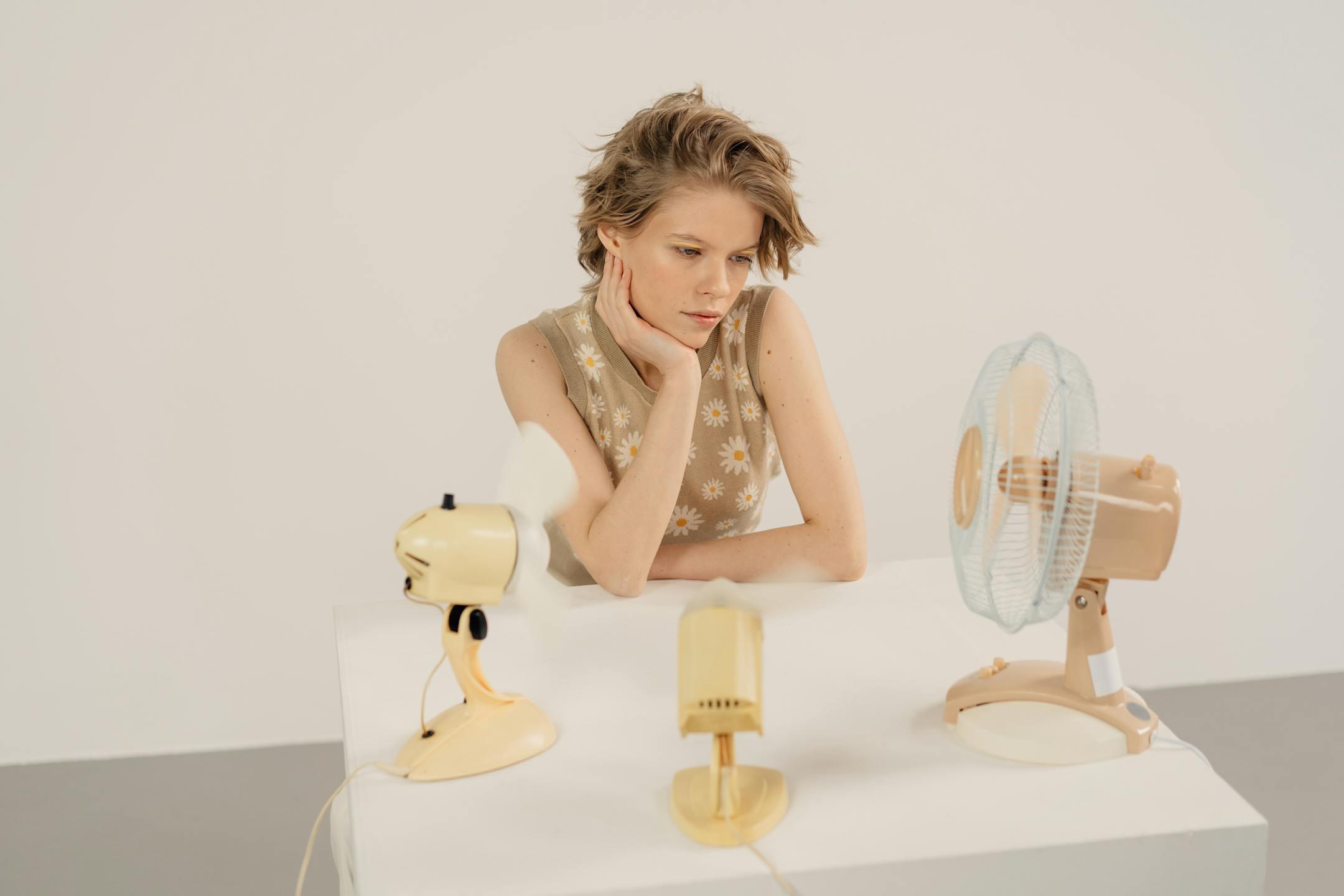 Thoughtful woman in a studio setting with vintage electric fans on display