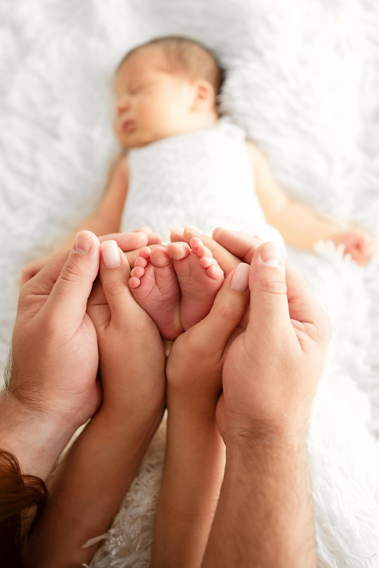 Tender moment of parents holding newborn's feet, symbolizing love and care.