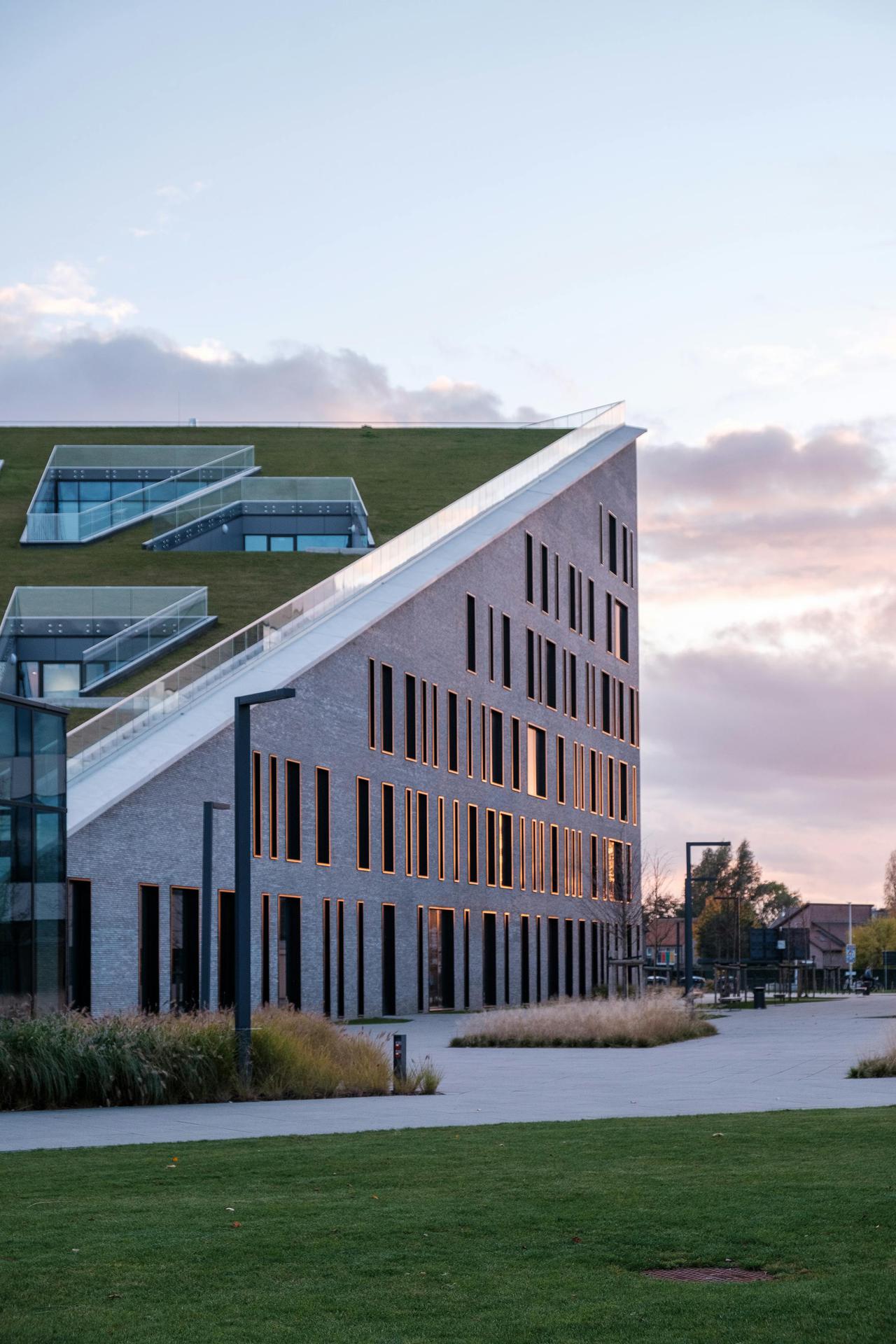 Elegant modern building with green roof at Corda Campus during dawn light in Hasselt.