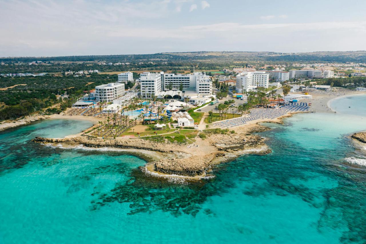Stunning aerial shot of a Cyprus seaside resort showcasing crystal clear waters and luxury hotels.