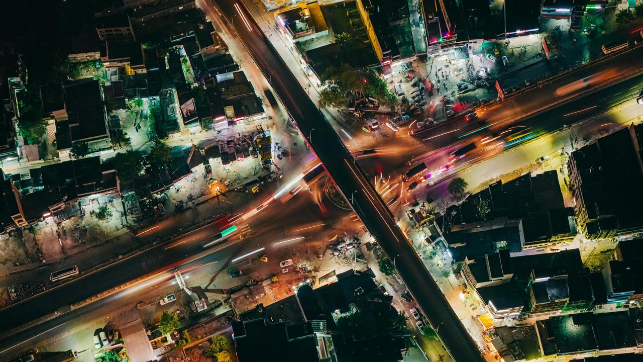 Dynamic aerial cityscape of a bustling night intersection in Muzaffarpur, showcasing vibrant light trails and urban infrastructure.