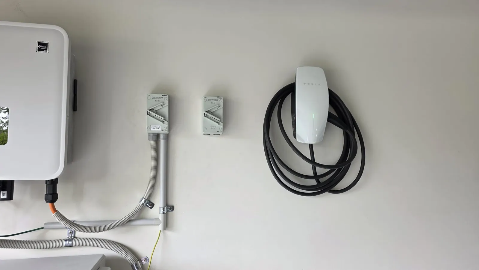 Tesla Wall Connector installed beside a solar inverter and AC isolators in a Rockbank garage