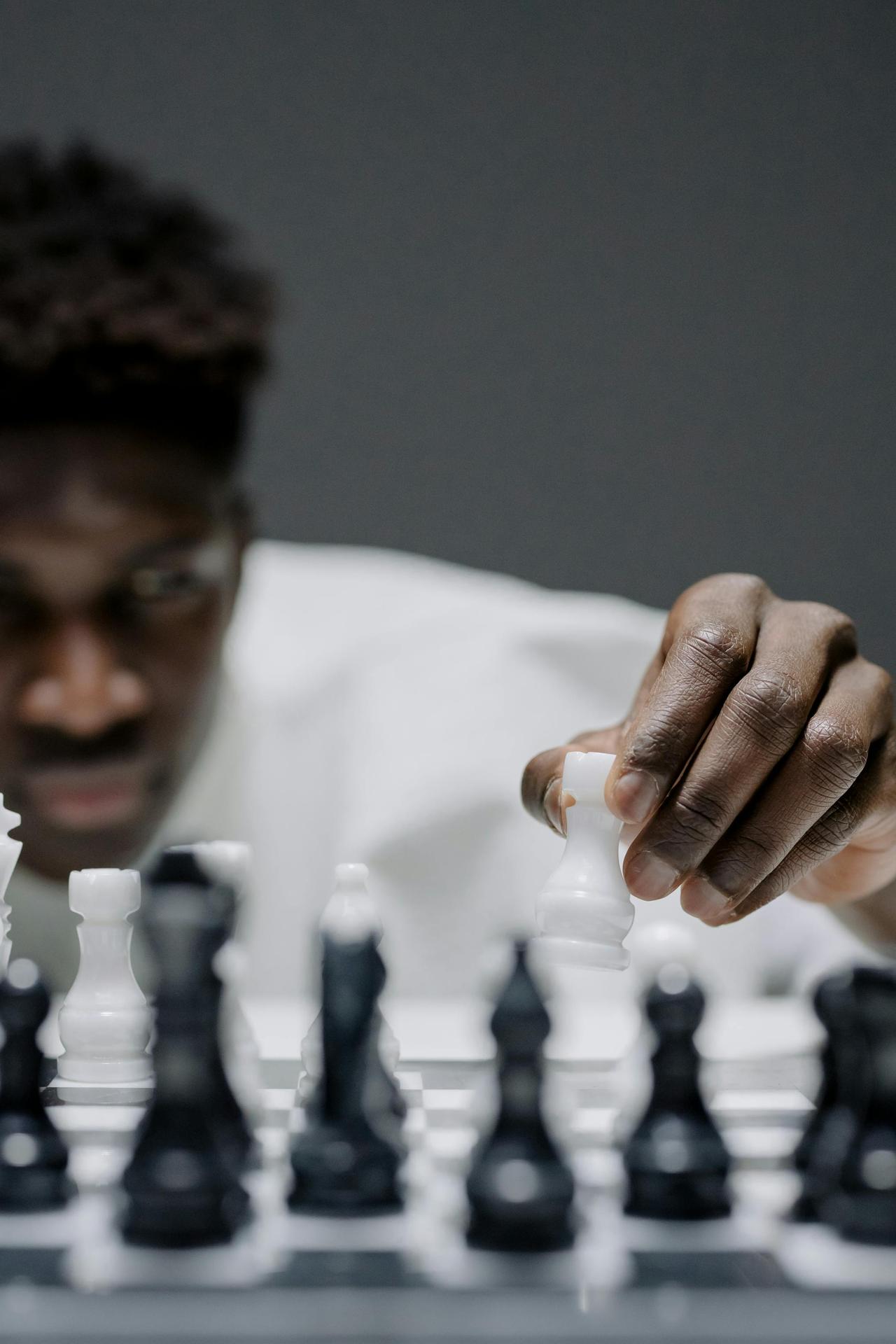 Close-up of a man concentrating on a chess move, showcasing strategy and focus.