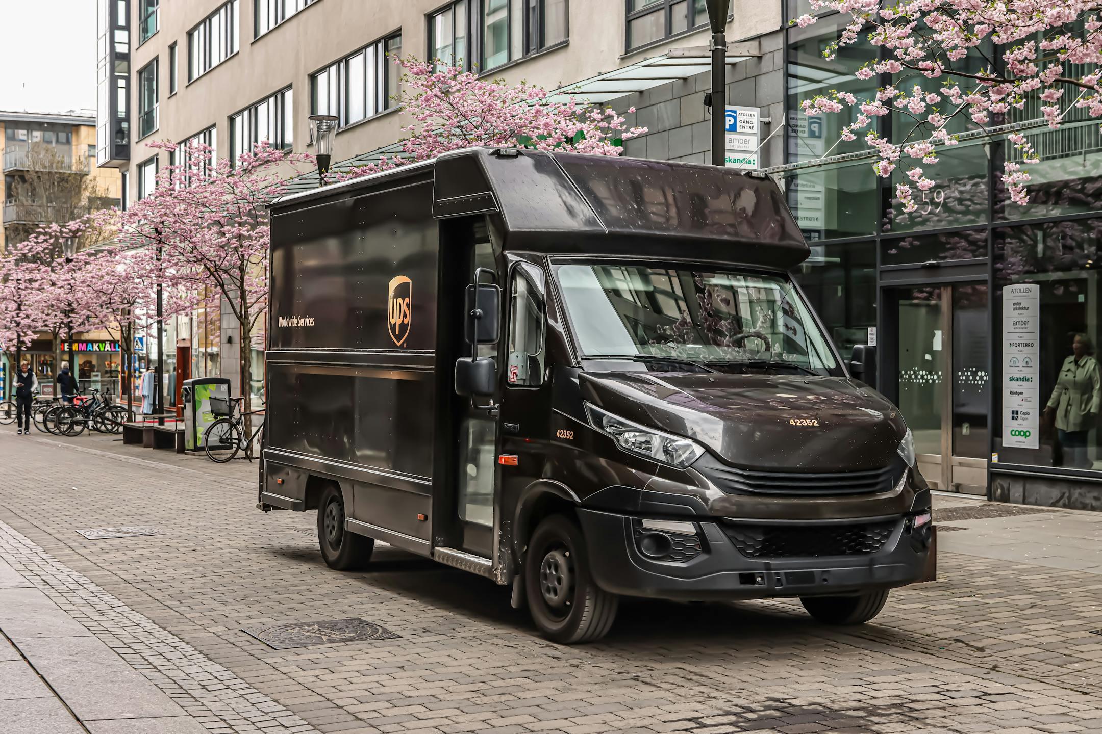 Black UPS delivery truck parked on a street in Jönköping, Sweden with cherry blossoms in spring.