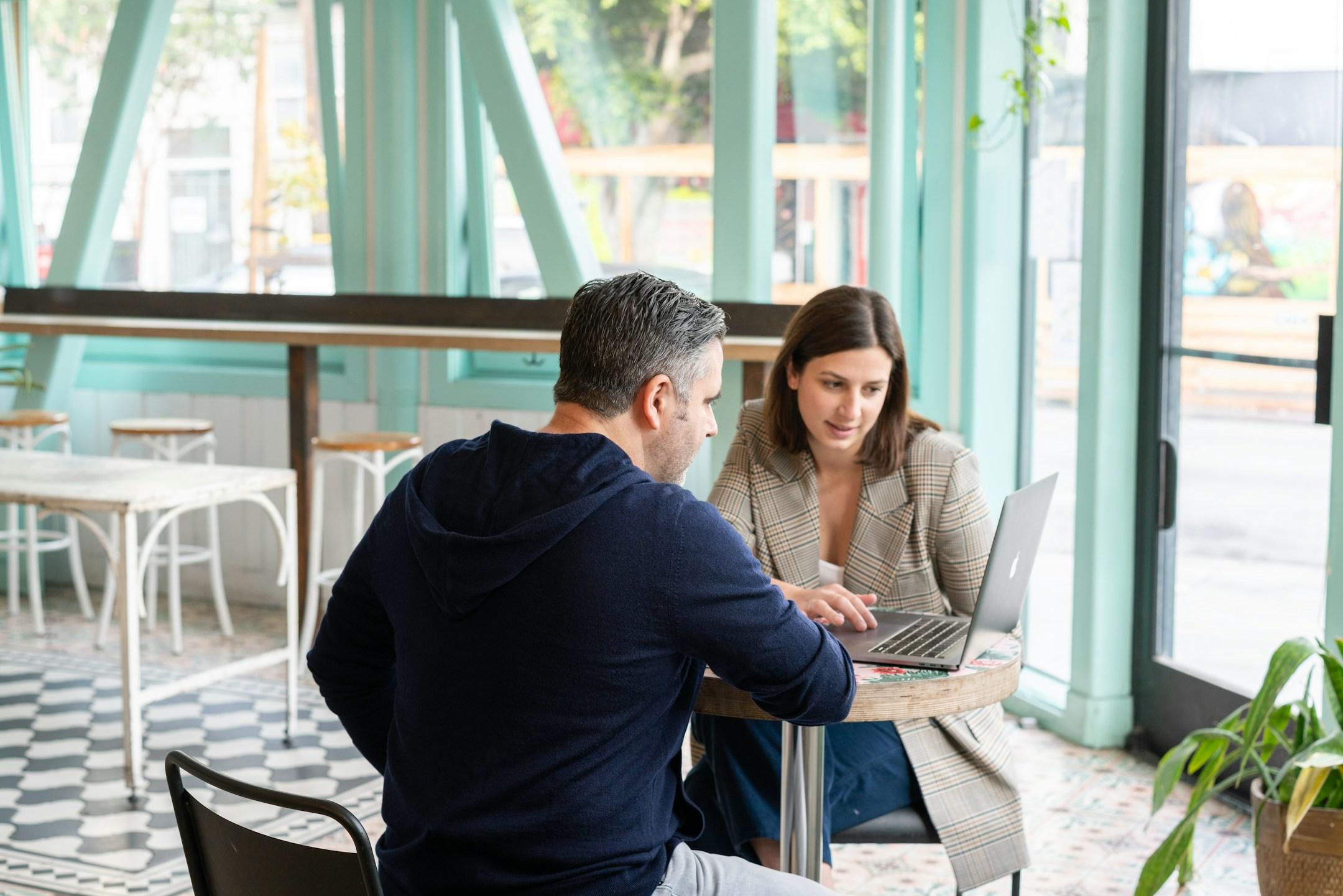 Businessman and businesswoman having a meeting in a cafe over a laptop