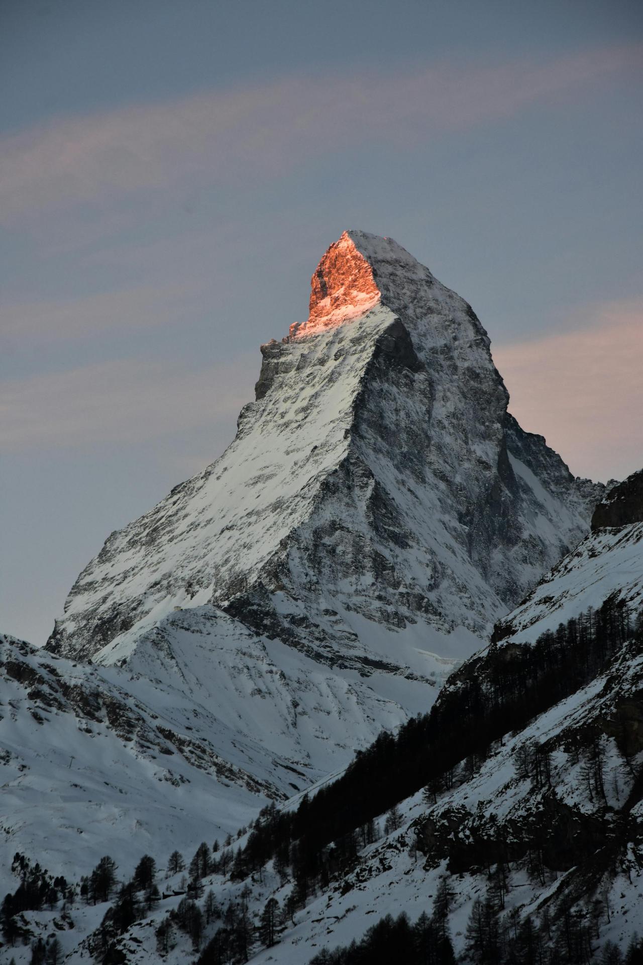 Stunning view of the snowcapped Matterhorn at sunrise, illuminating the peak in a warm glow, Zermatt, Switzerland.