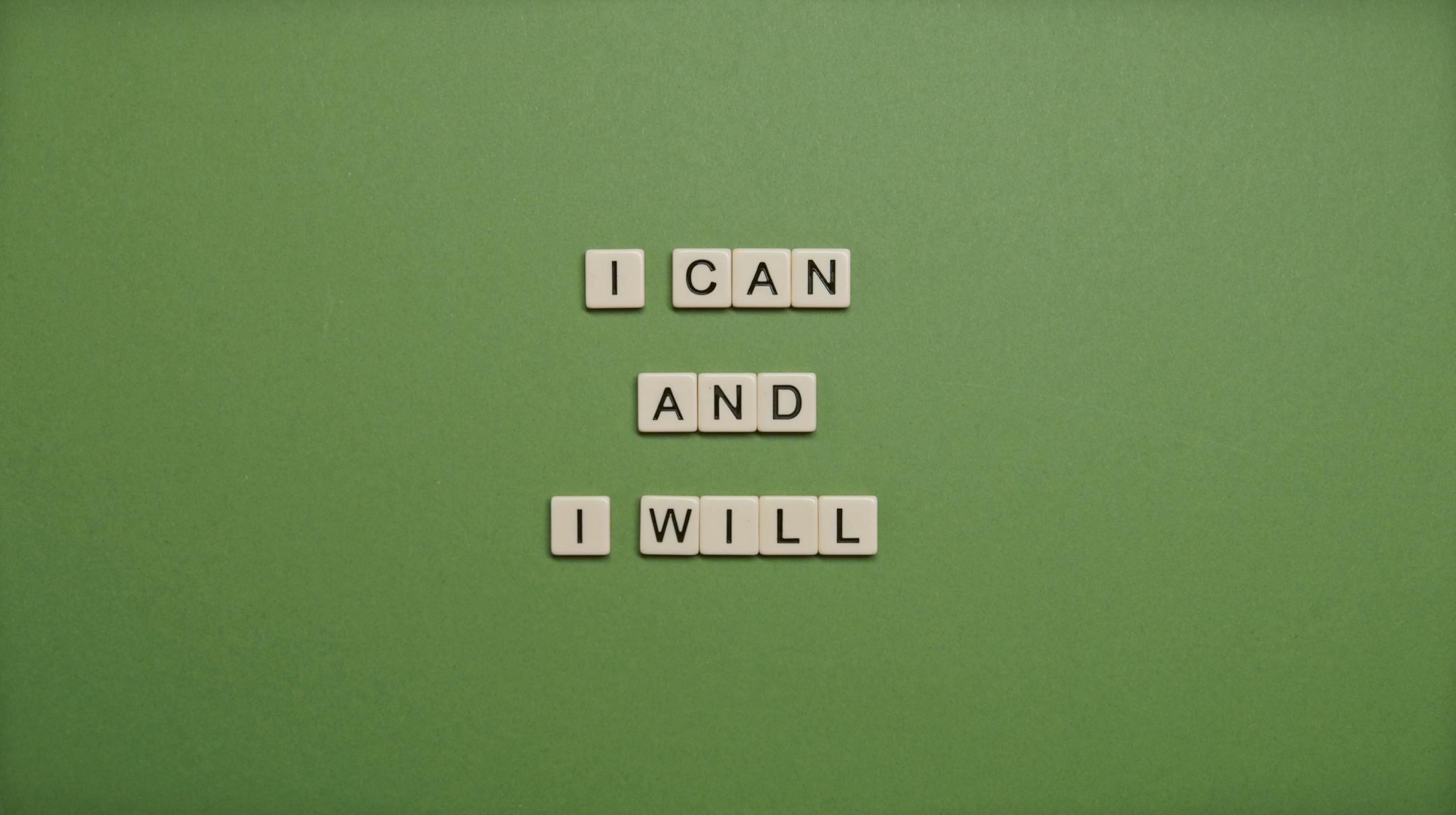 Inspirational message 'I Can and I Will' spelled with tile letters on a green background.