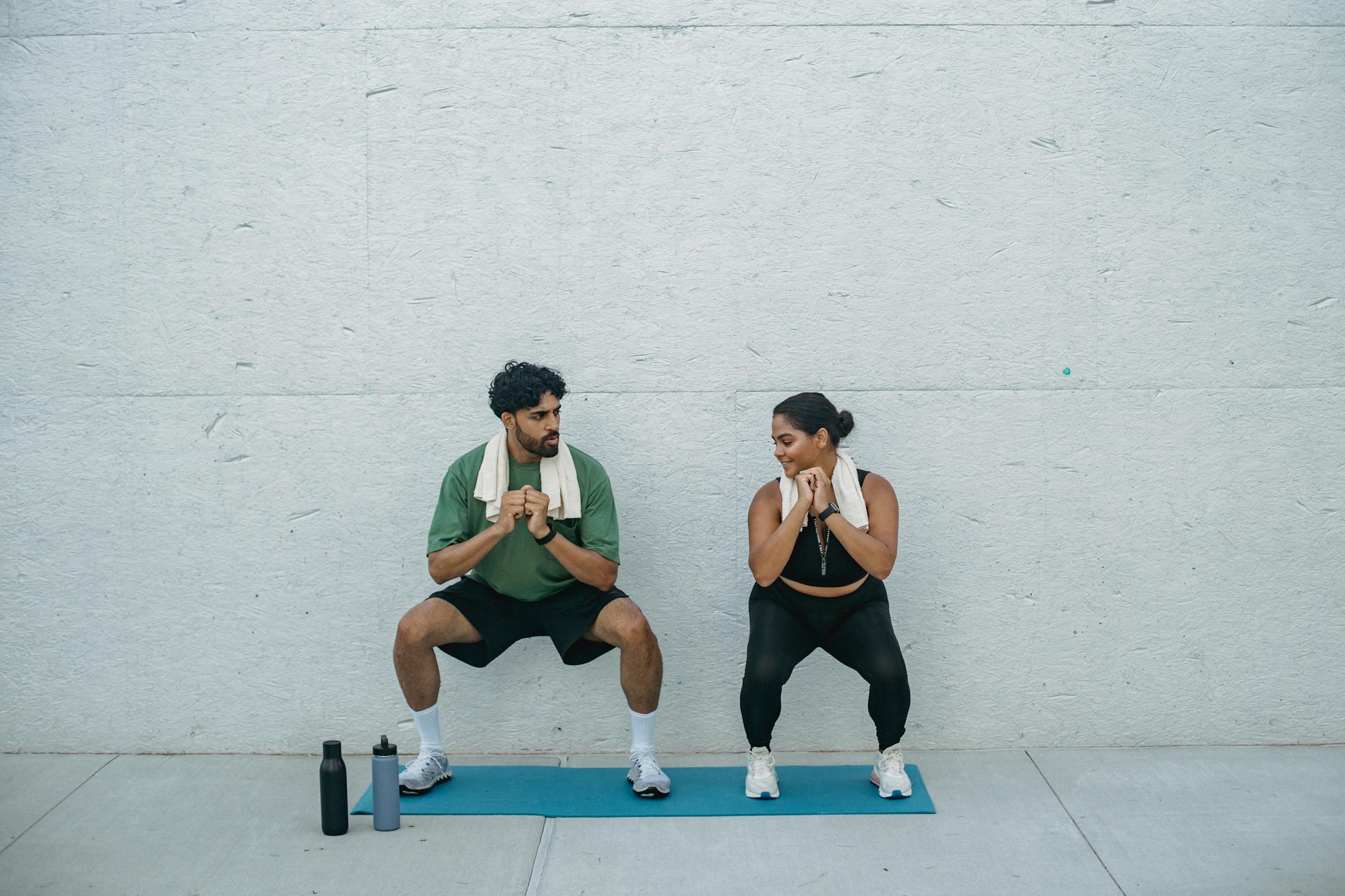 Man and woman exercising outdoors on a yoga mat, focusing on squats and healthy lifestyle.