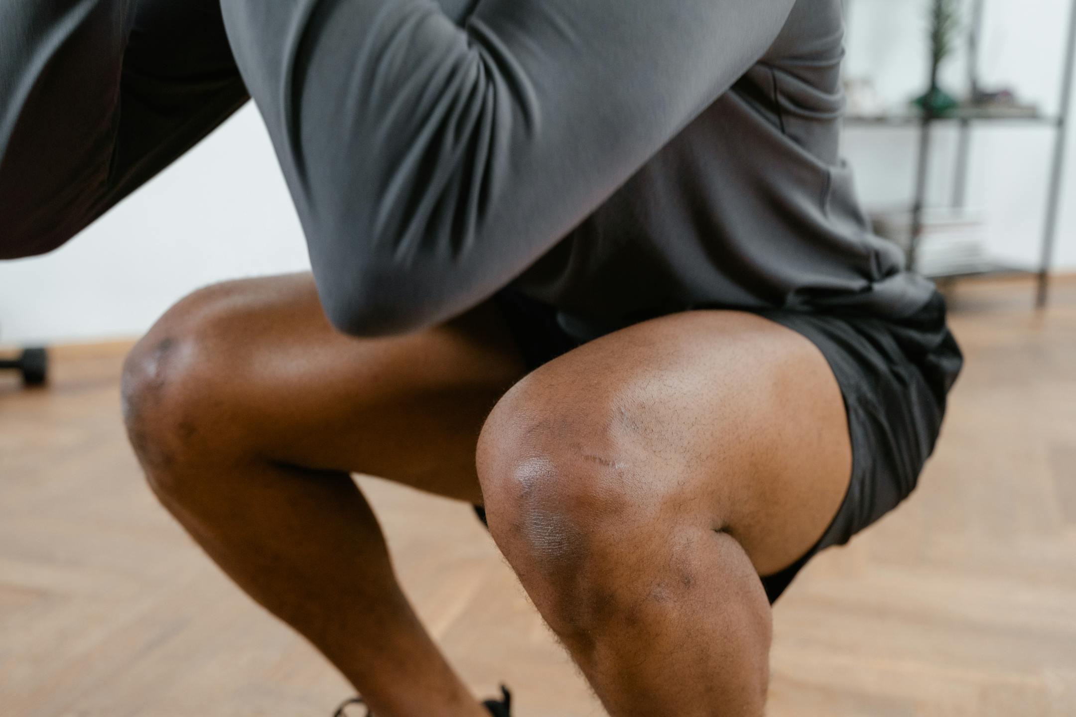 A focused view of a male athlete performing squats in a gym setting, emphasizing fitness and strength.