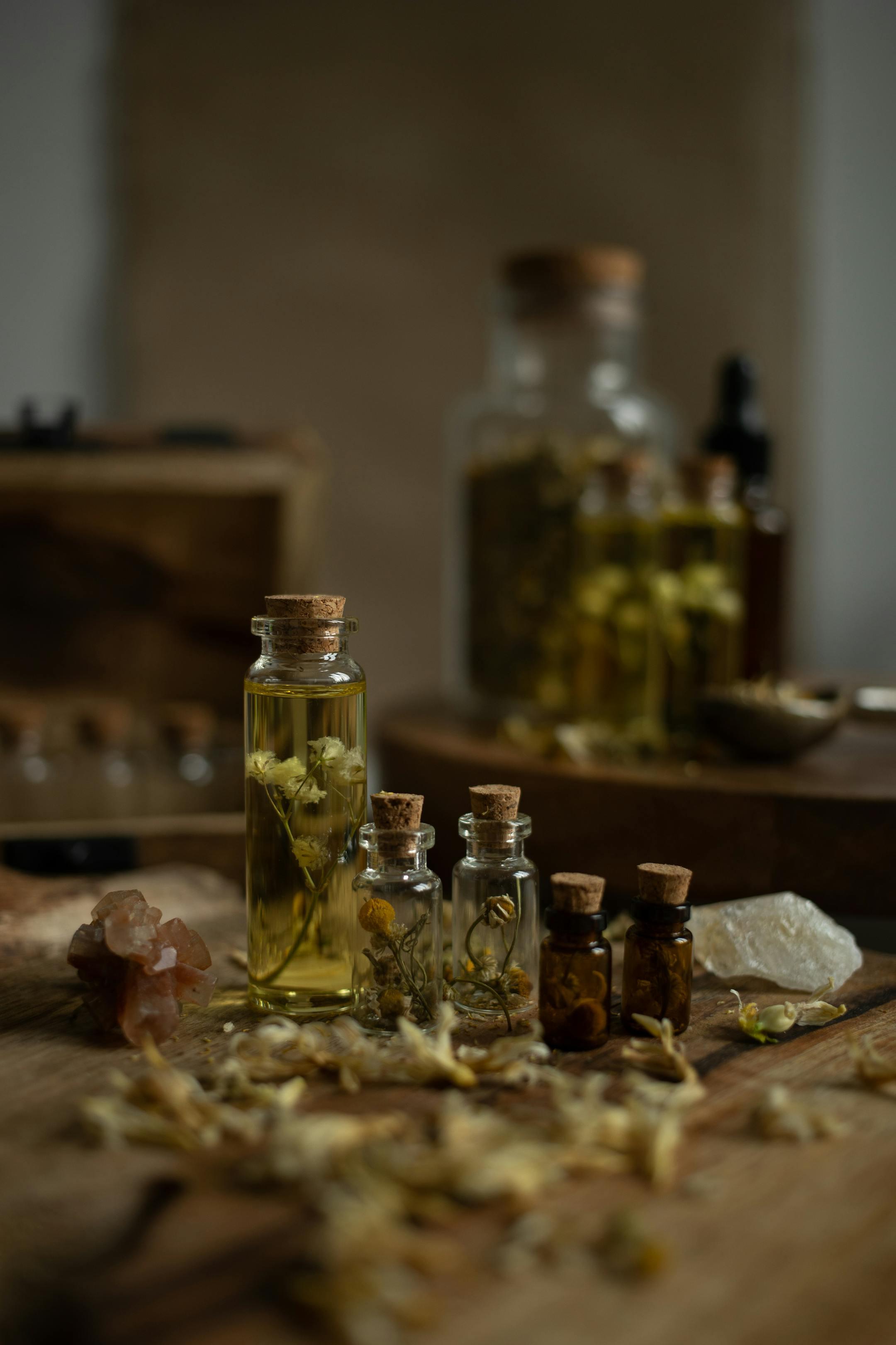 A collection of rustic glass bottles with aromatic herbs on a wooden table, perfect for aromatherapy themes.