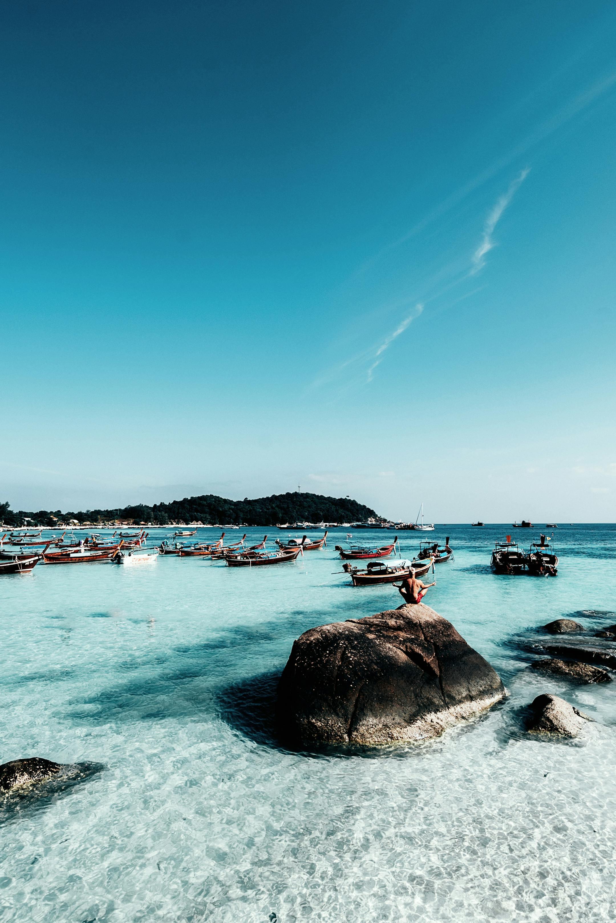 Explore the crystal-clear waters and scenic beauty of Koh Lipe, Thailand, with traditional boats dotting the coastline.