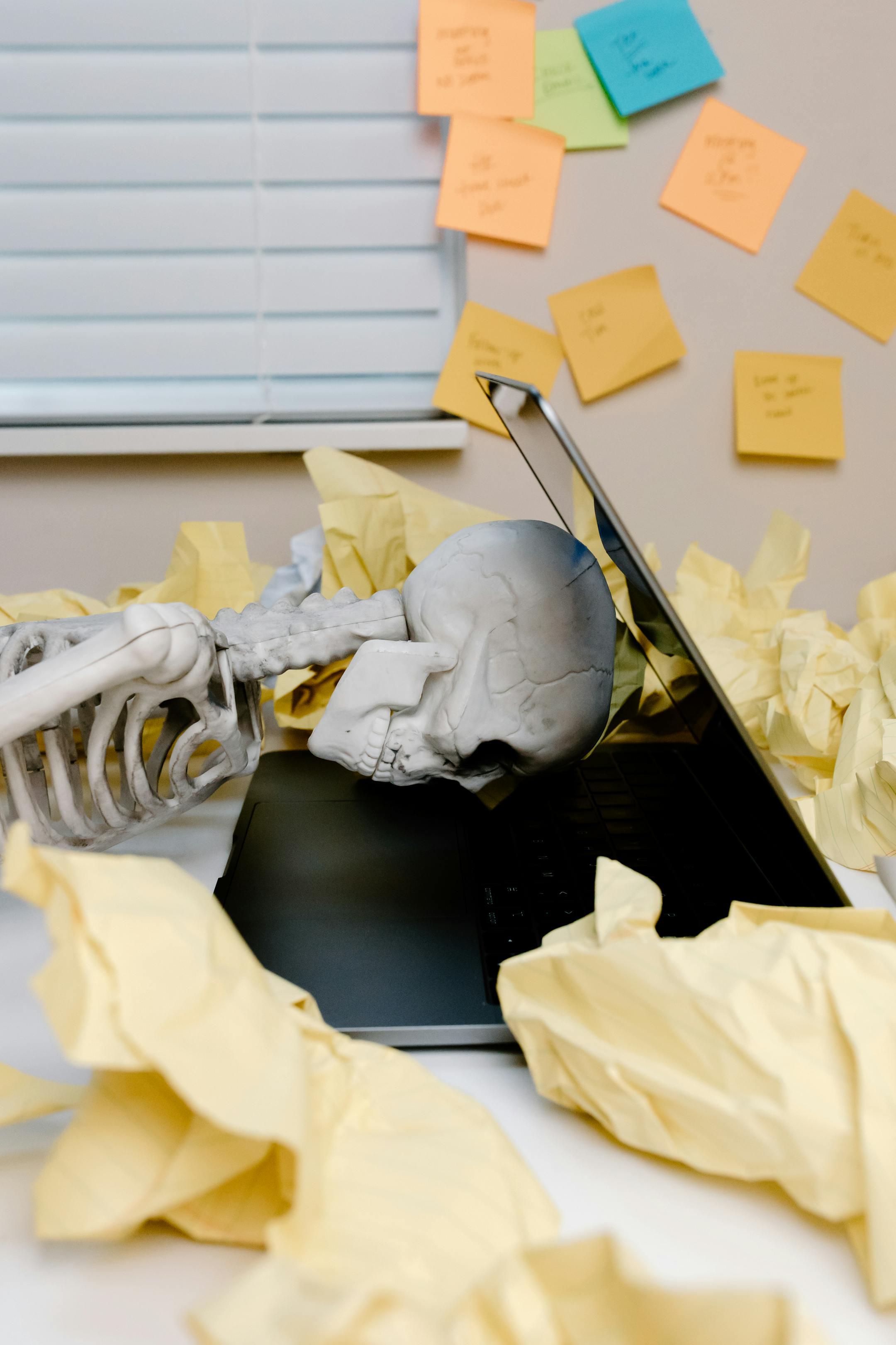 Humorous scene of skeleton at laptop, highlighting work burnout and fatigue.