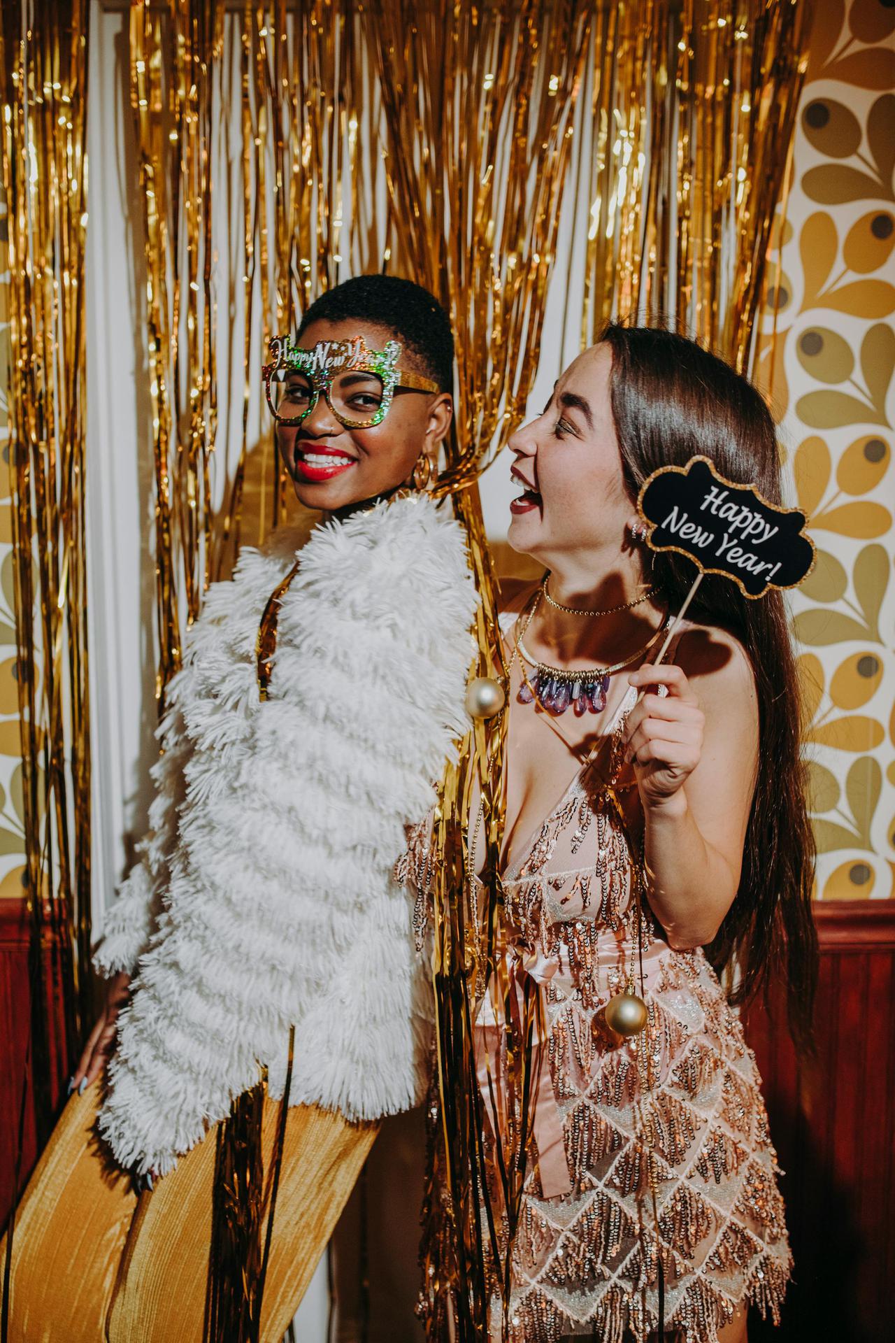 Guests posing in a Full House Entertainment photo booth with fun props and a shimmering gold backdrop.