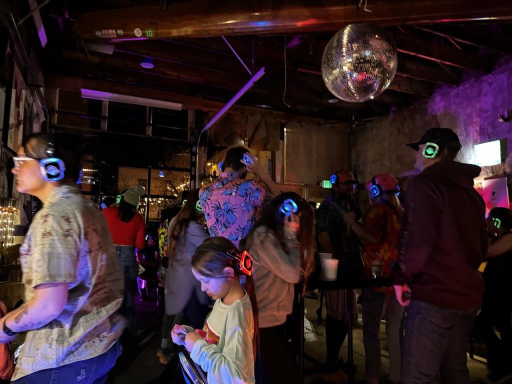 Guests dancing with wireless Silent Disco headphones under purple lights at a Full House Entertainment event.