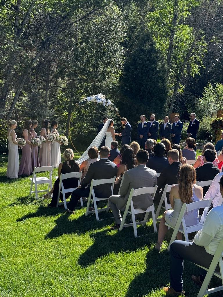 Outdoor wedding ceremony in the Colorado mountains with guests seated and couple exchanging vows.