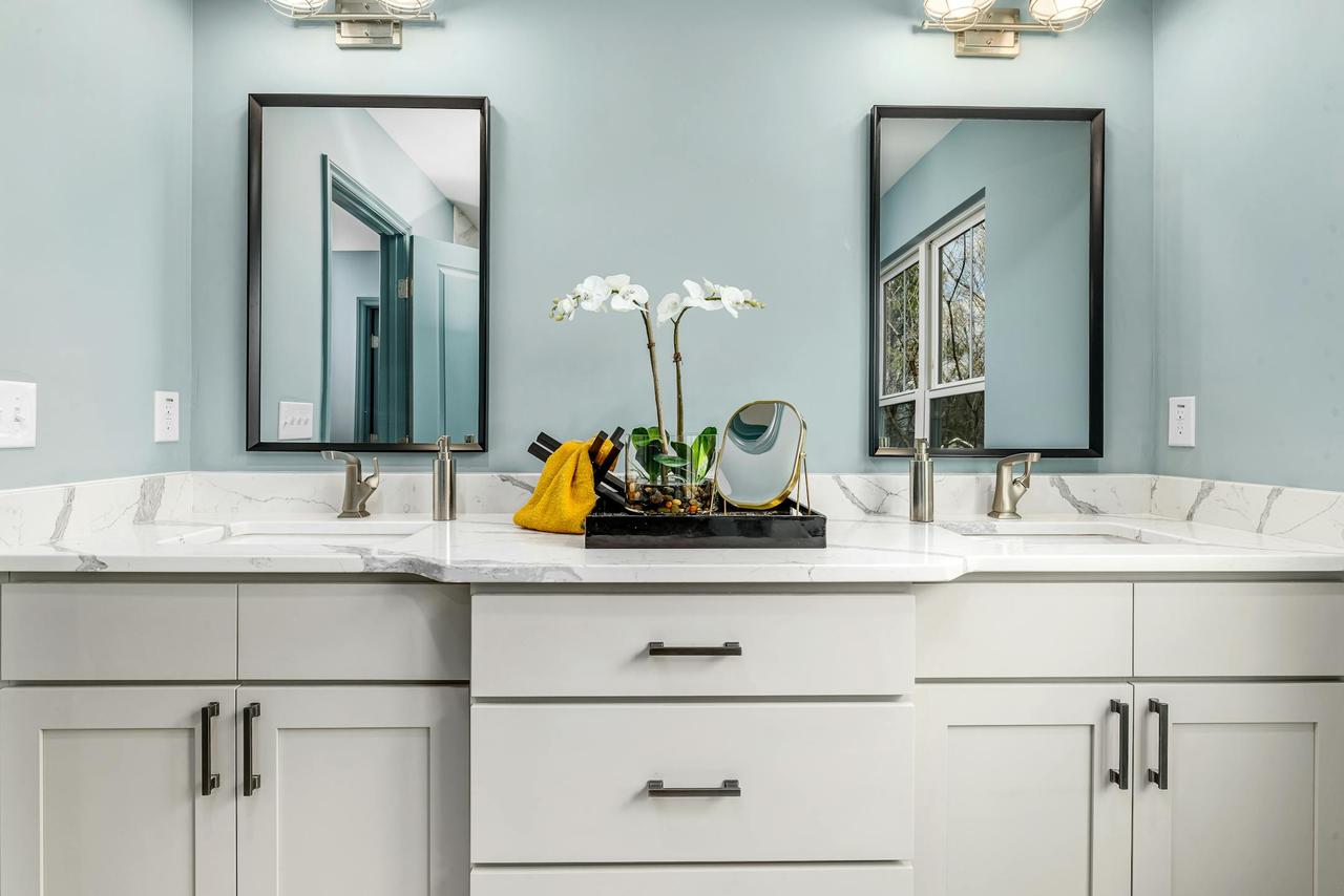 A serene modern bathroom featuring twin sinks, elegant faucets, and decorative mirrors.