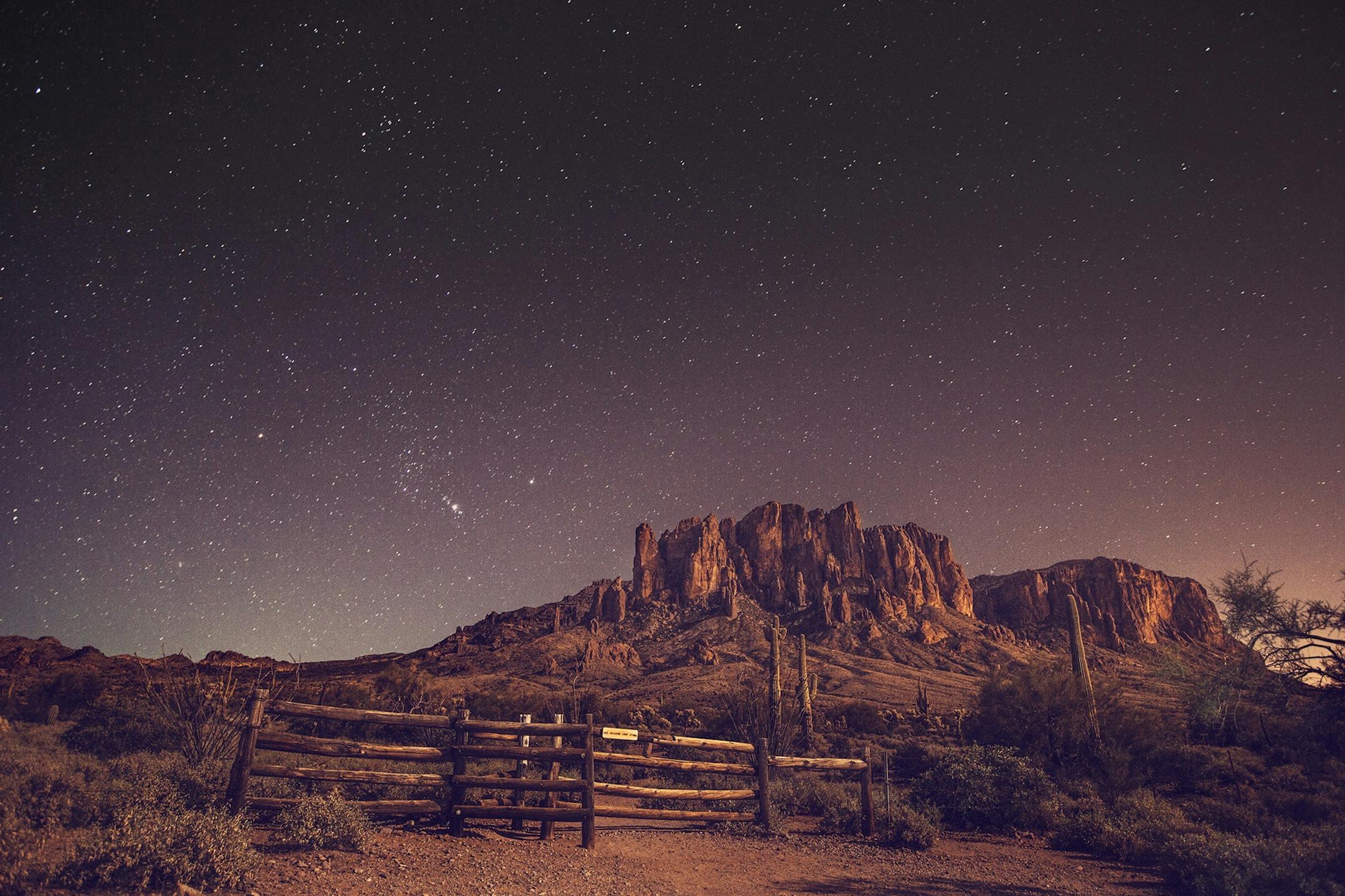 A breathtaking night sky above the Superstition Mountains with a starry desert landscape.