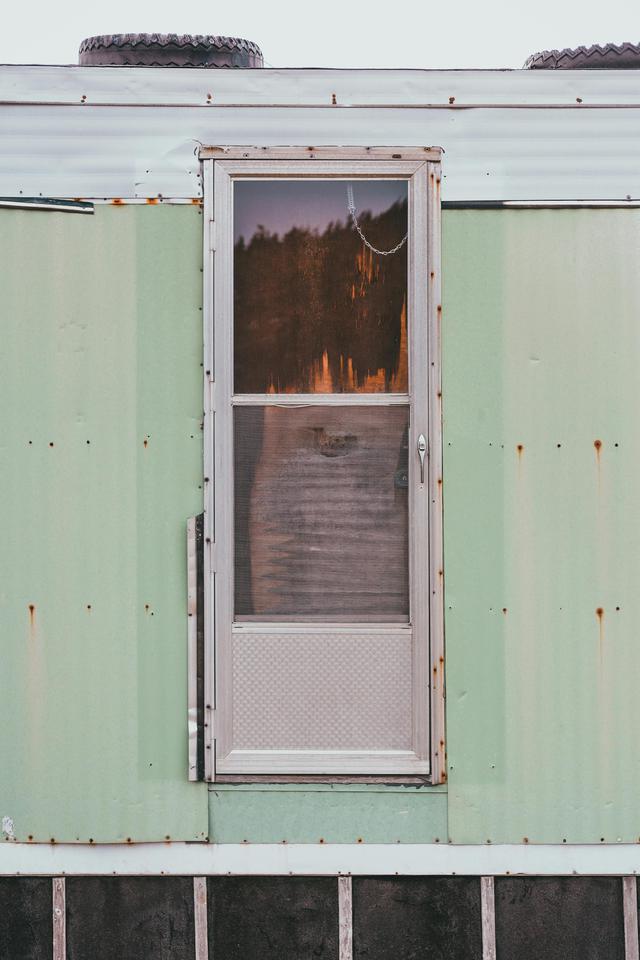Rustic vintage door on a retro green mobile home, showcasing classic architecture.