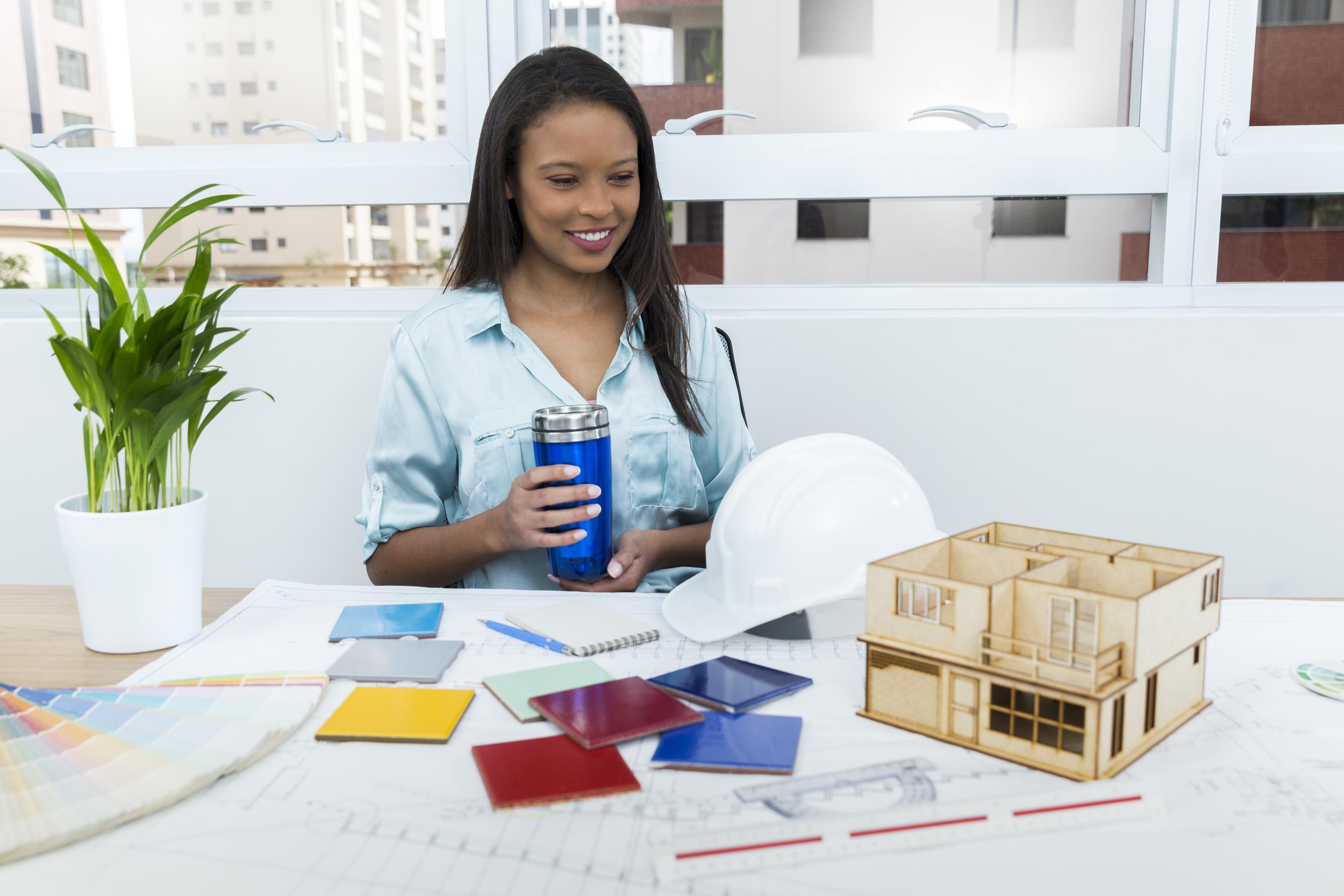 happy-african-american-lady-chair-with-vacuum-cup-near-plan-model-house-table.jpg