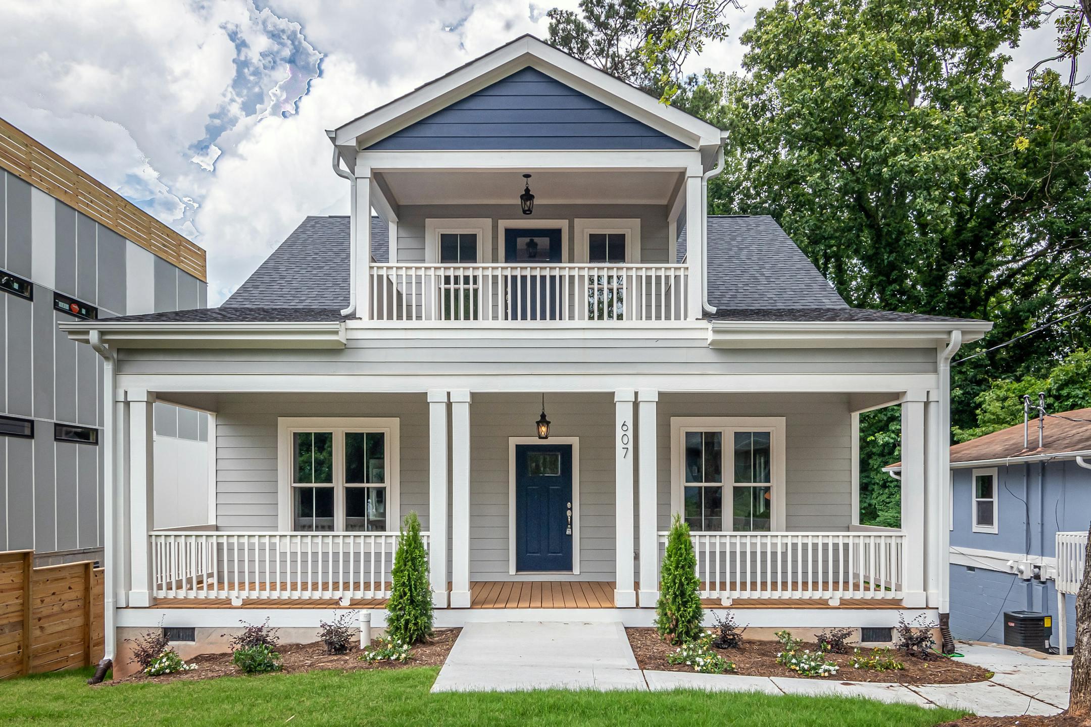 Front view of a modern two-story family home featuring a balcony and spacious porch.