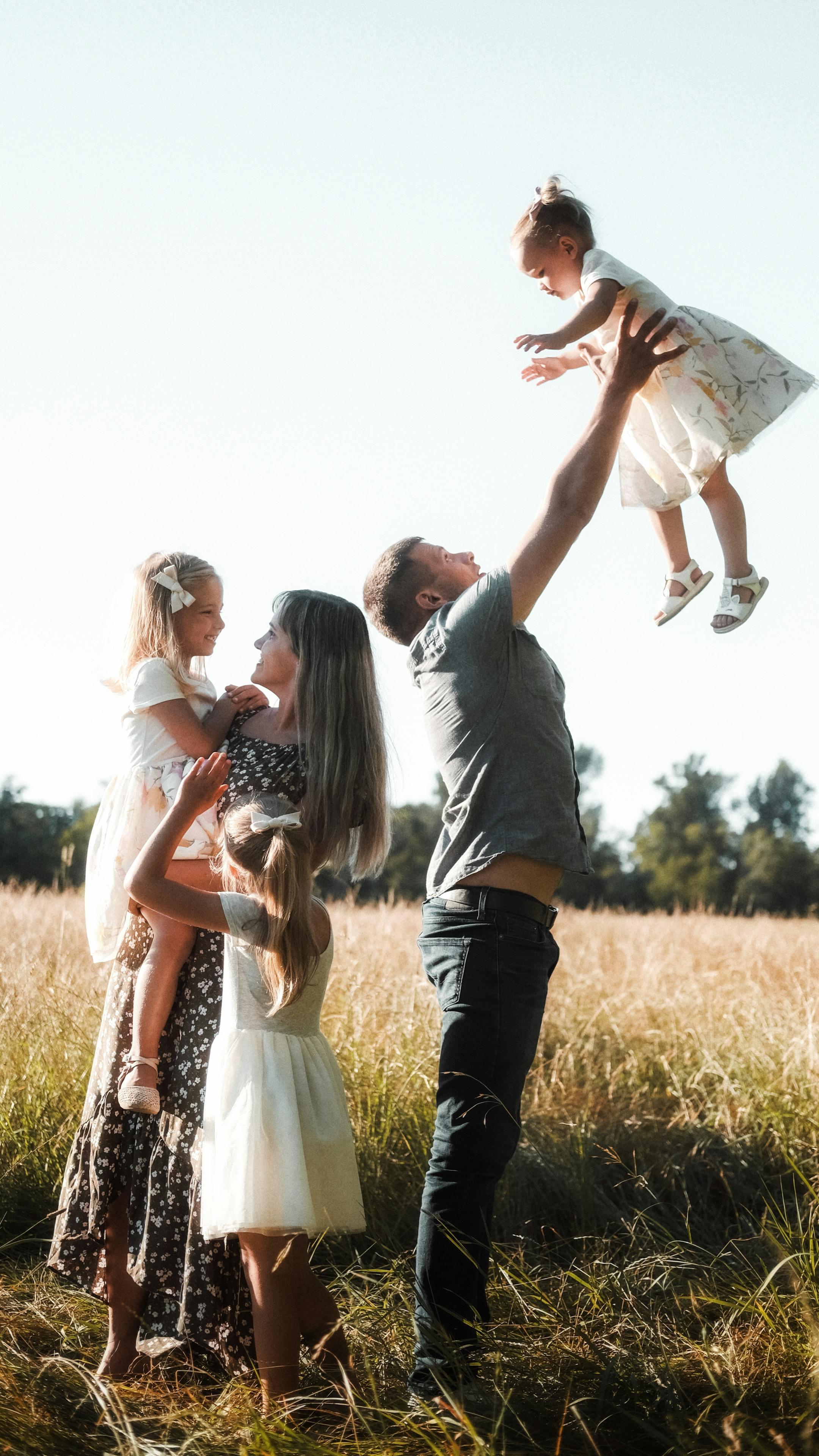 A joyful family playing together outdoors on a sunny day in a scenic field.