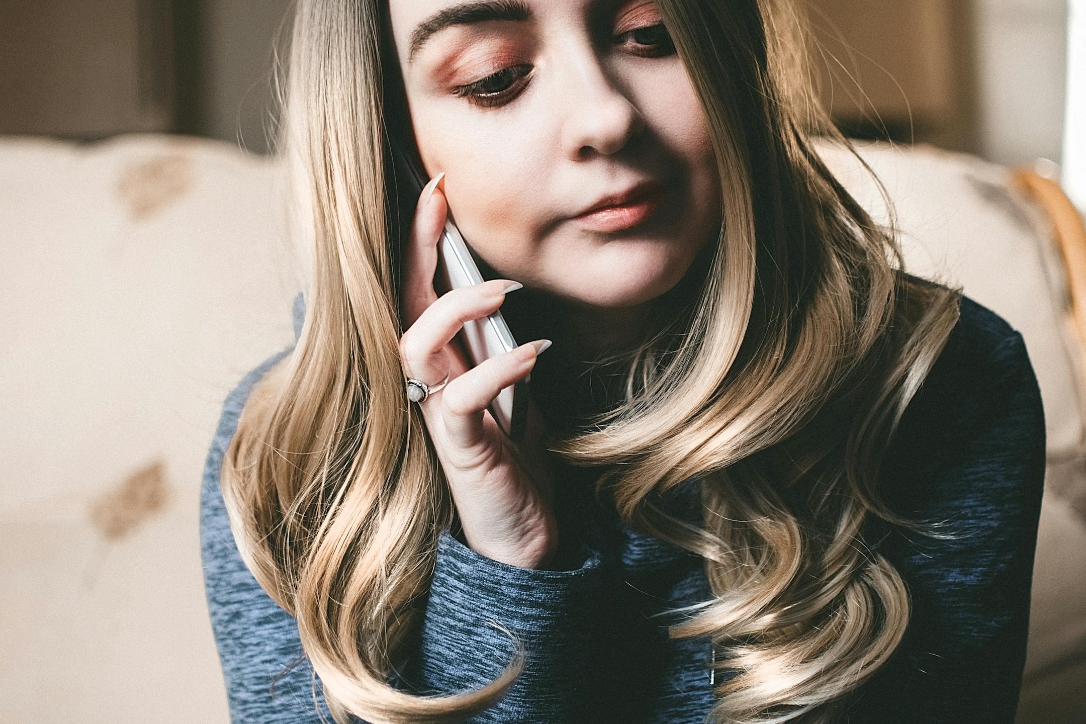Close-up of a young woman talking on a smartphone indoors, showcasing elegance and focus.