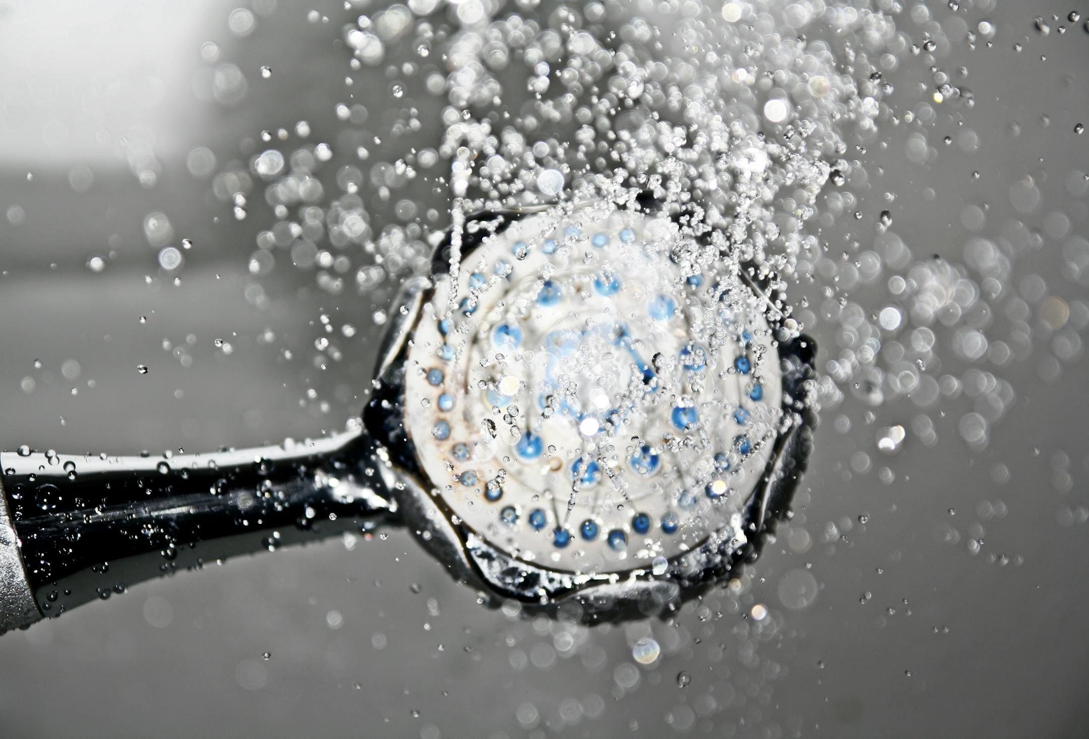Shower plumbing installation in Coventry - close-up of fitted shower head with running water.