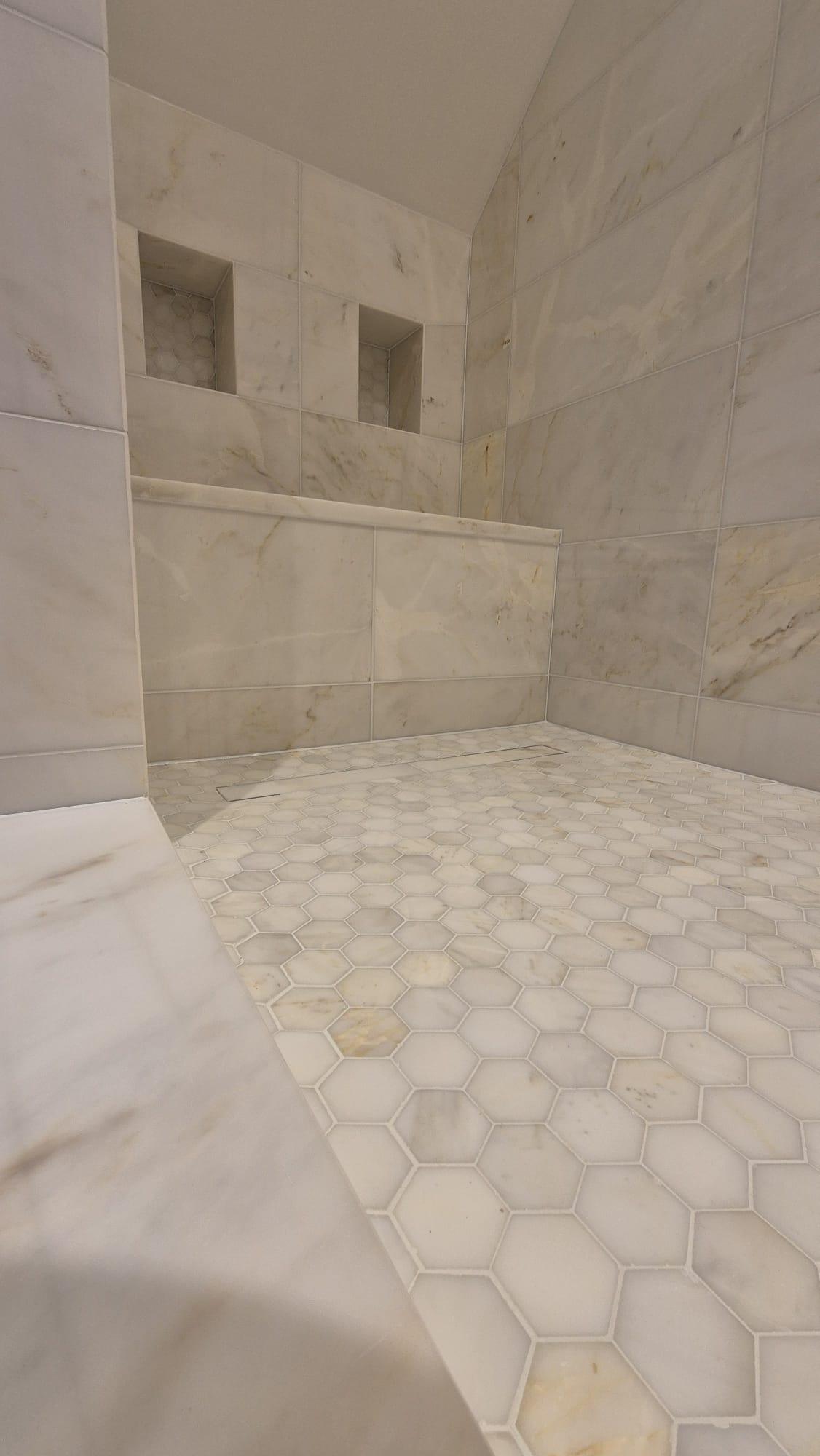 Luxury marble wet room in Kenilworth with epoxy mitred corners, mosaic floor, and large marble wall tiles - premium tiling installation.