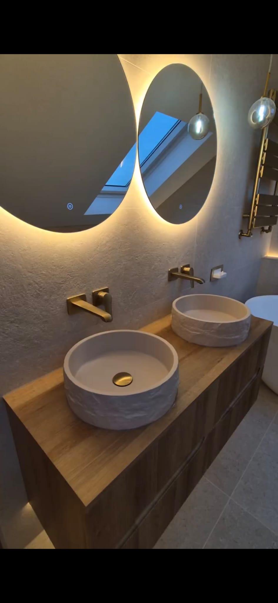 Large format tiling behind bathroom vanity with backlit oval mirrors, Coventry Tiling