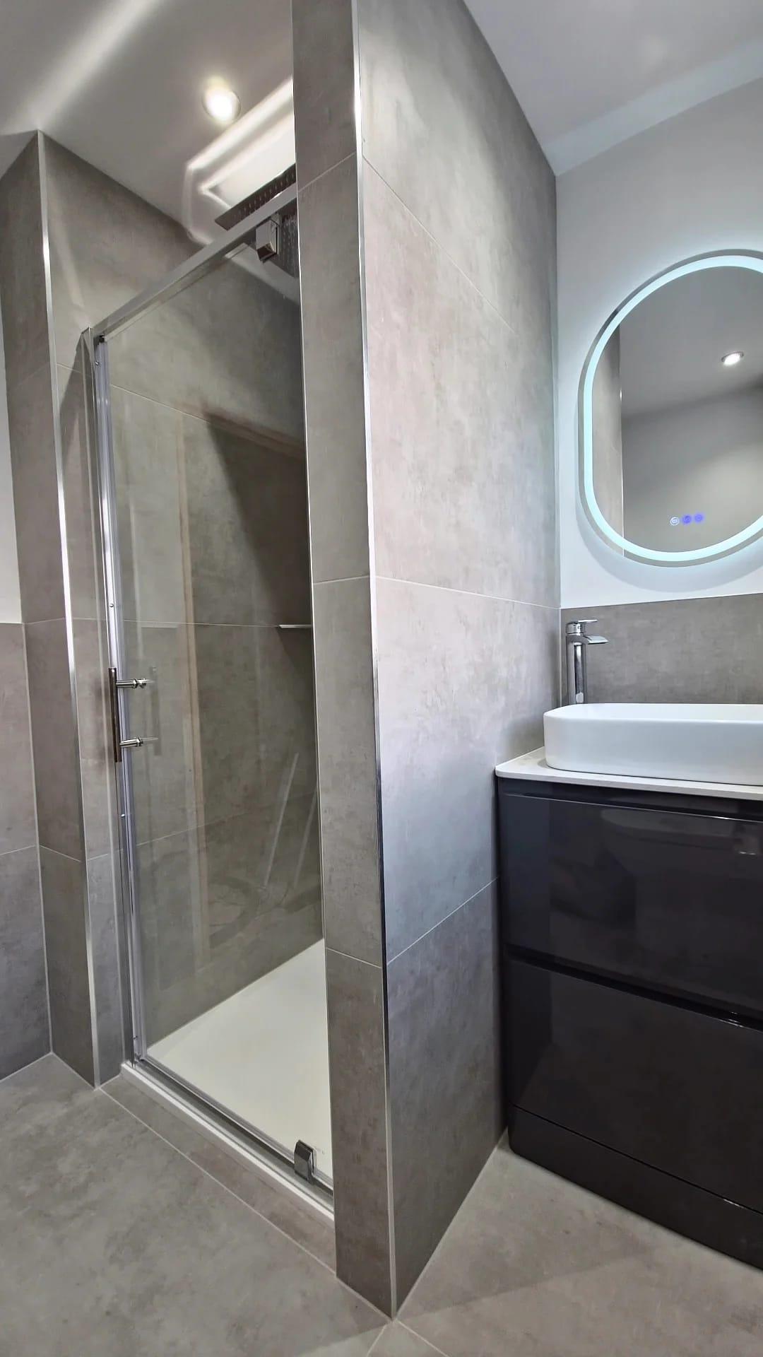 Textured concrete-effect tiling with glass shower door in a modern bathroom, Coventry Tiling