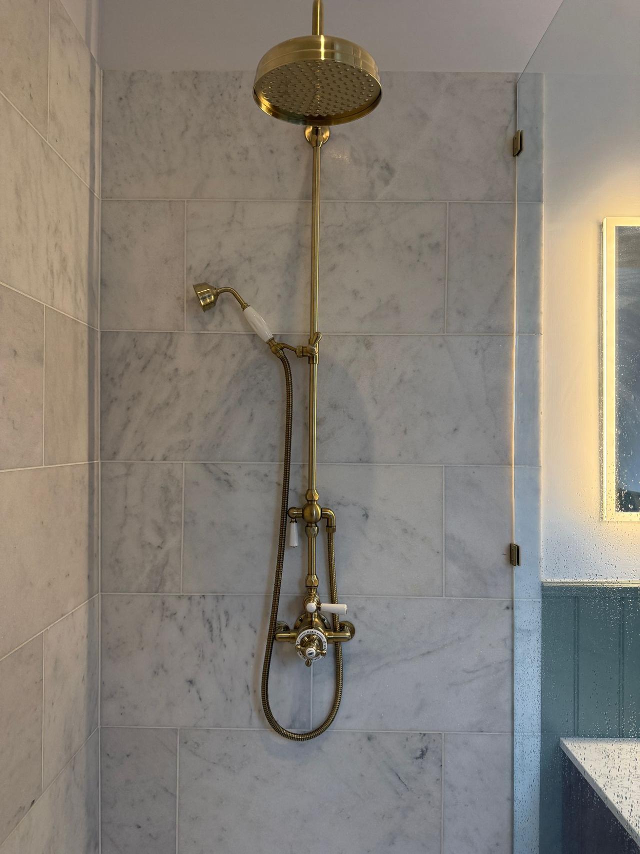 Luxury marble shower room with brushed brass fittings, tiled by Coventry Tiling in Kenilworth.