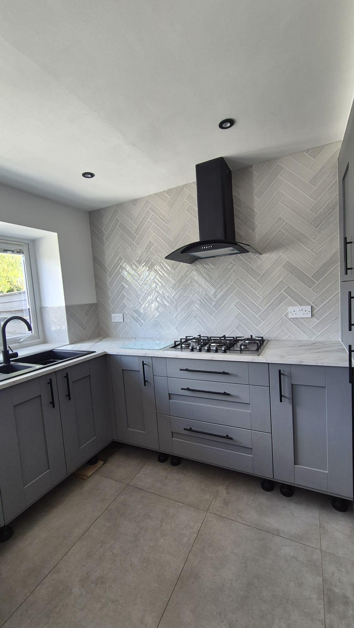 Herringbone-pattern tiled splashback behind hob in kitchen, Coventry Tiling