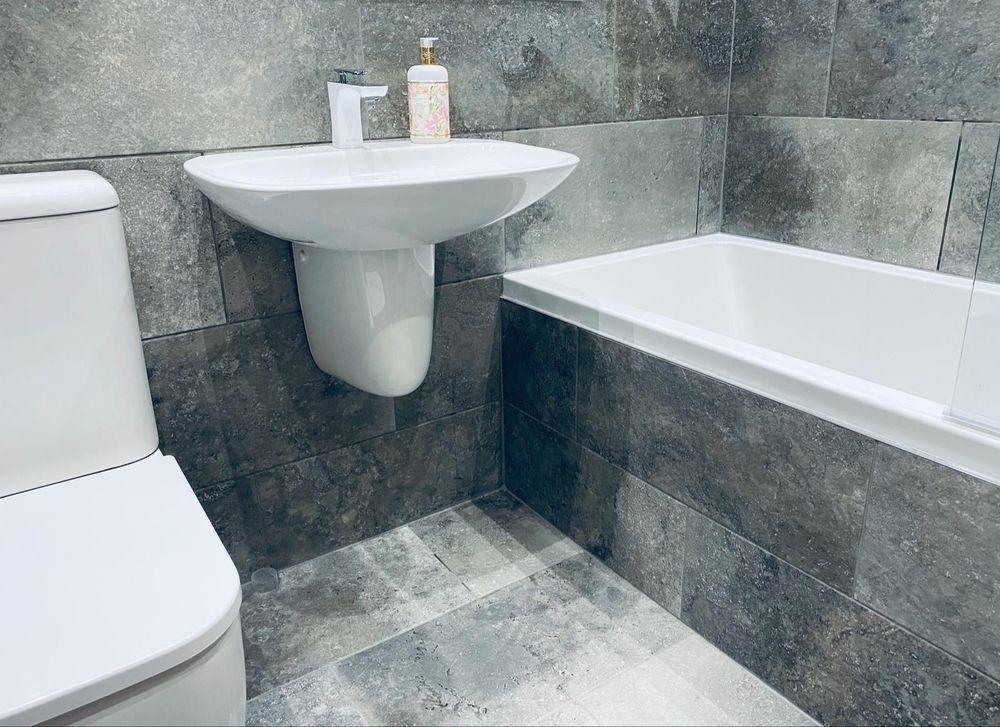 Modern grey tiled bathroom in Coventry with large-format wall tiles and a matching tiled floor, installed to a flawless finish.