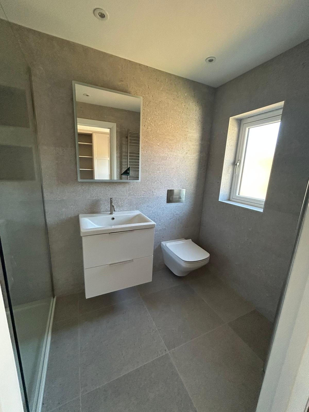 Ensuite bathroom in Solihull with walk-in shower, wall-hung toilet, and modern wall tiling