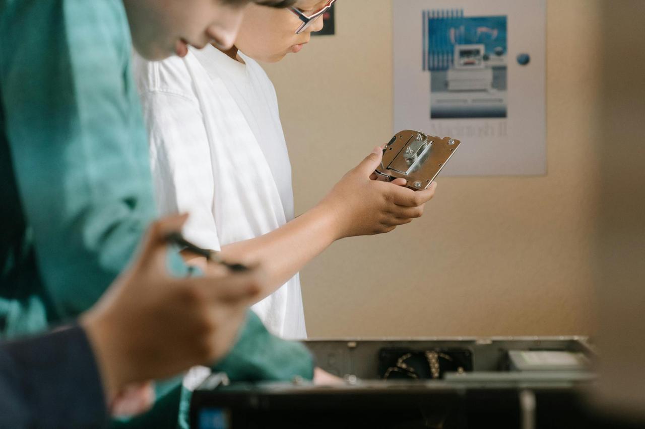 Children exploring computer hardware parts during a tech workshop indoors.