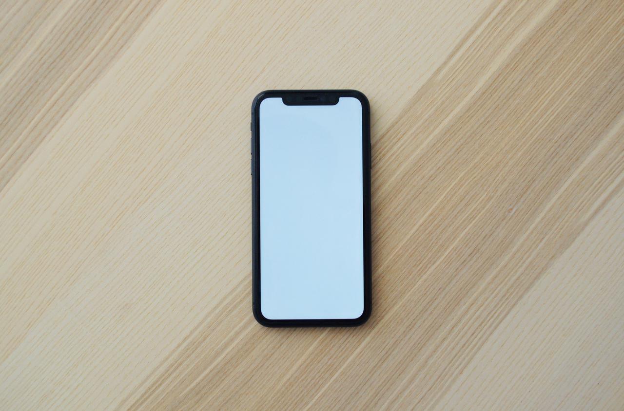 A cell phone on the wooden table.