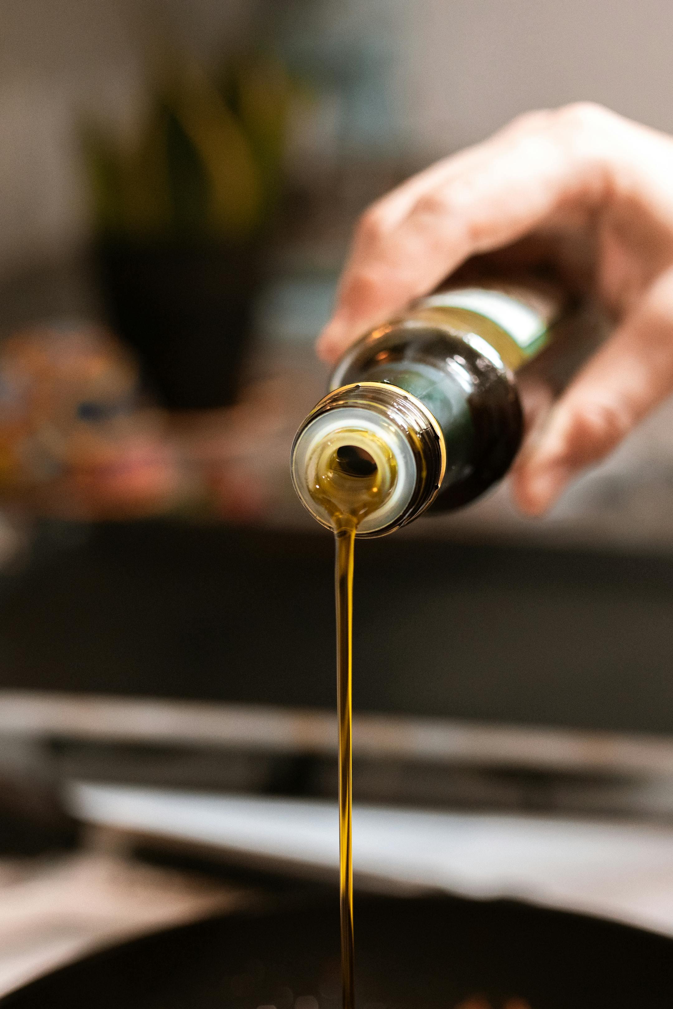 A close-up shot of olive oil being poured into a pan, highlighting healthy cooking.