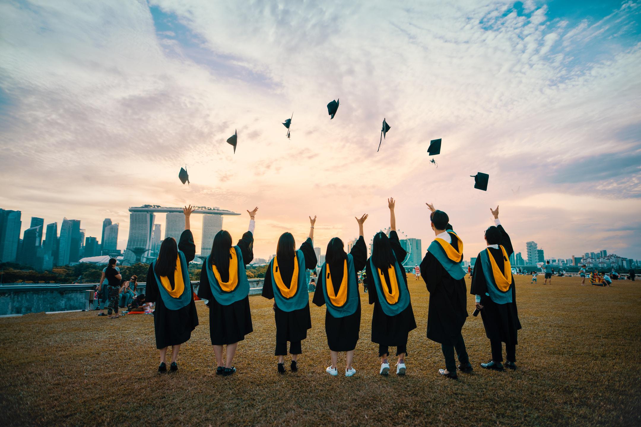 Image of students throwing graduation caps into the air on their way to higher education because of college counseling services.