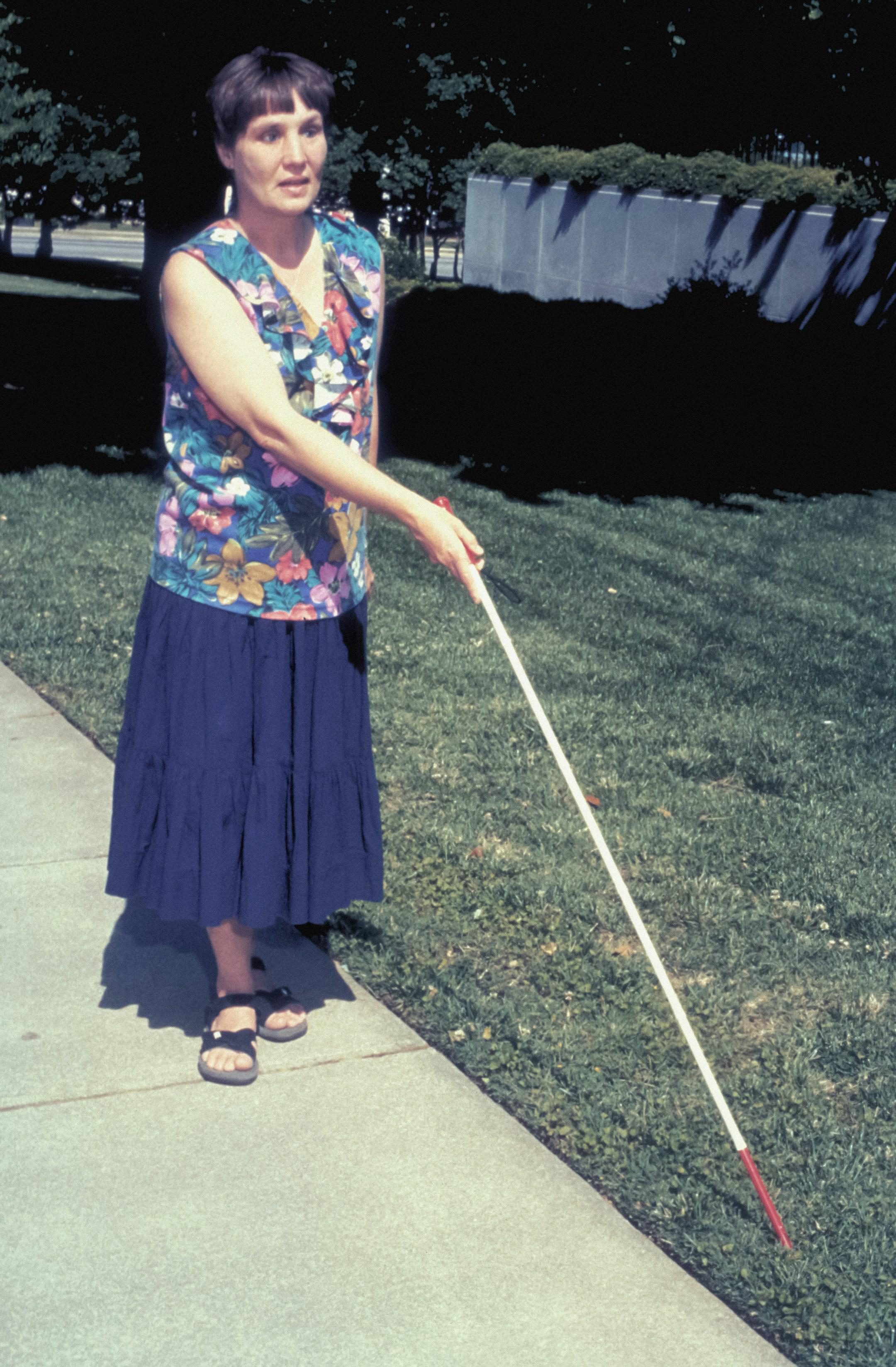A visually impaired woman using a walking stick