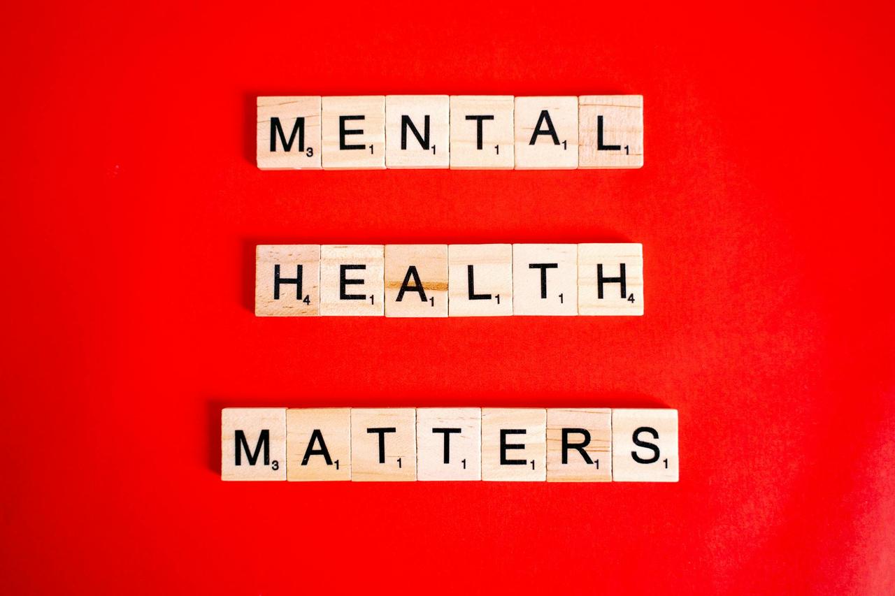 Wooden tiles spelling 'Mental Health Matters' on a vivid red background.