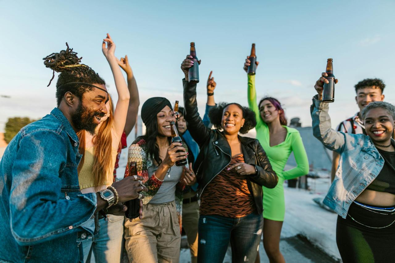 A lively group of friends celebrating with drinks on a sunny rooftop party.